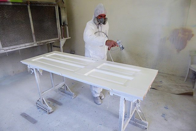 Maler lackiert eine Tür in der Werkstatt